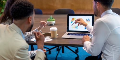 Financial advisor or lawyer with couple explaining options. They are discussing finance charts and graphs on a laptop computer. They sitting in an office and are discussing something with the agent