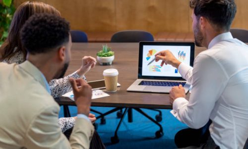 Financial advisor or lawyer with couple explaining options. They are discussing finance charts and graphs on a laptop computer. They sitting in an office and are discussing something with the agent